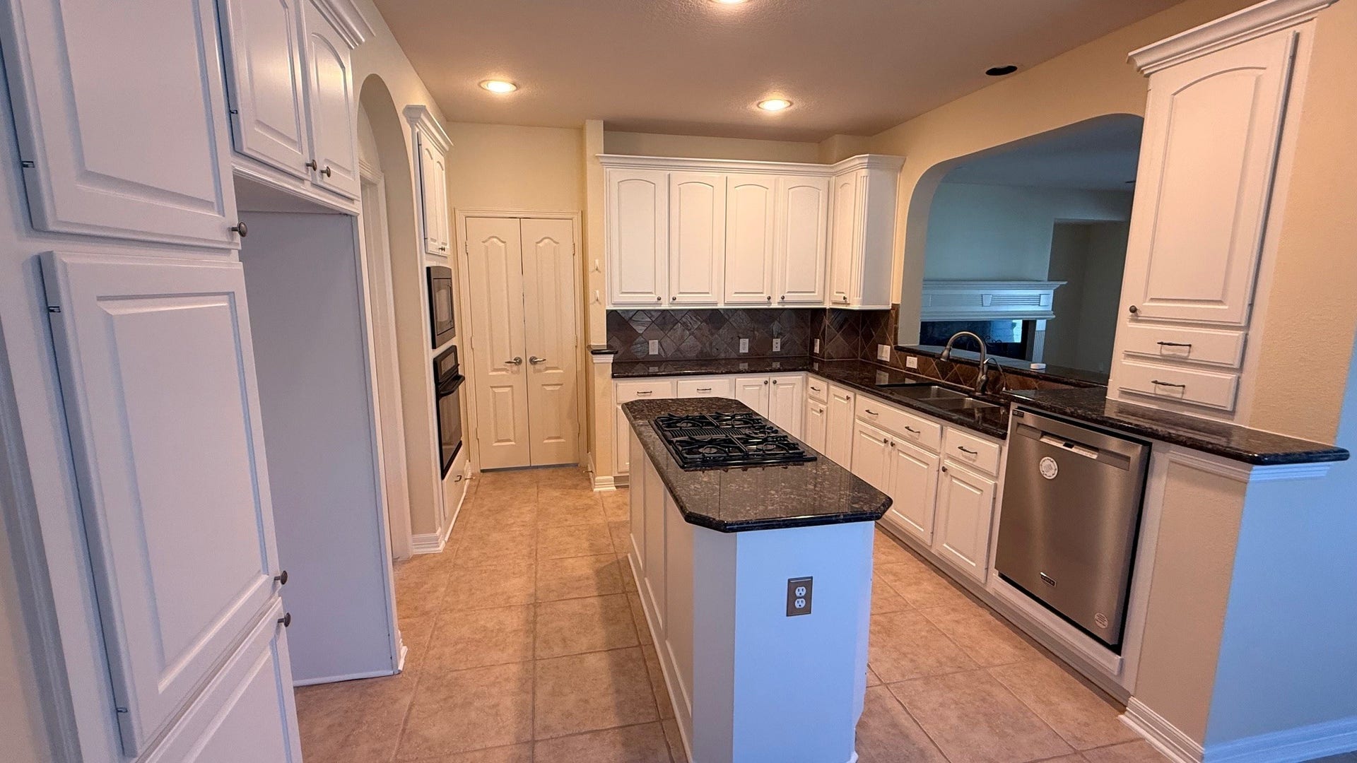 21603 Statfield Glen, Katy, TX 77450 Featuring a center island with a gas cooktop, this kitchen boasts stunning granite countertops and tall cabinets finished with elegant crown molding.