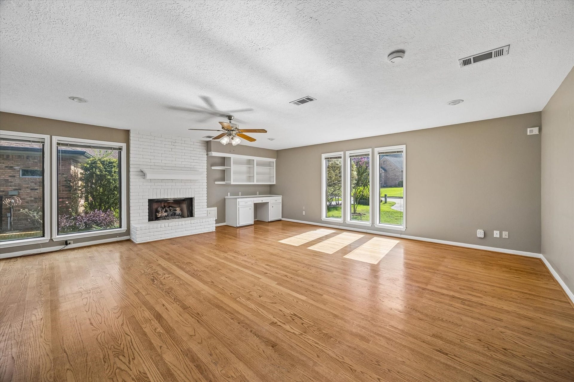 Spacious downstairs game room with a fireplace, abundant natural light and large windows that create a bright, inviting space.