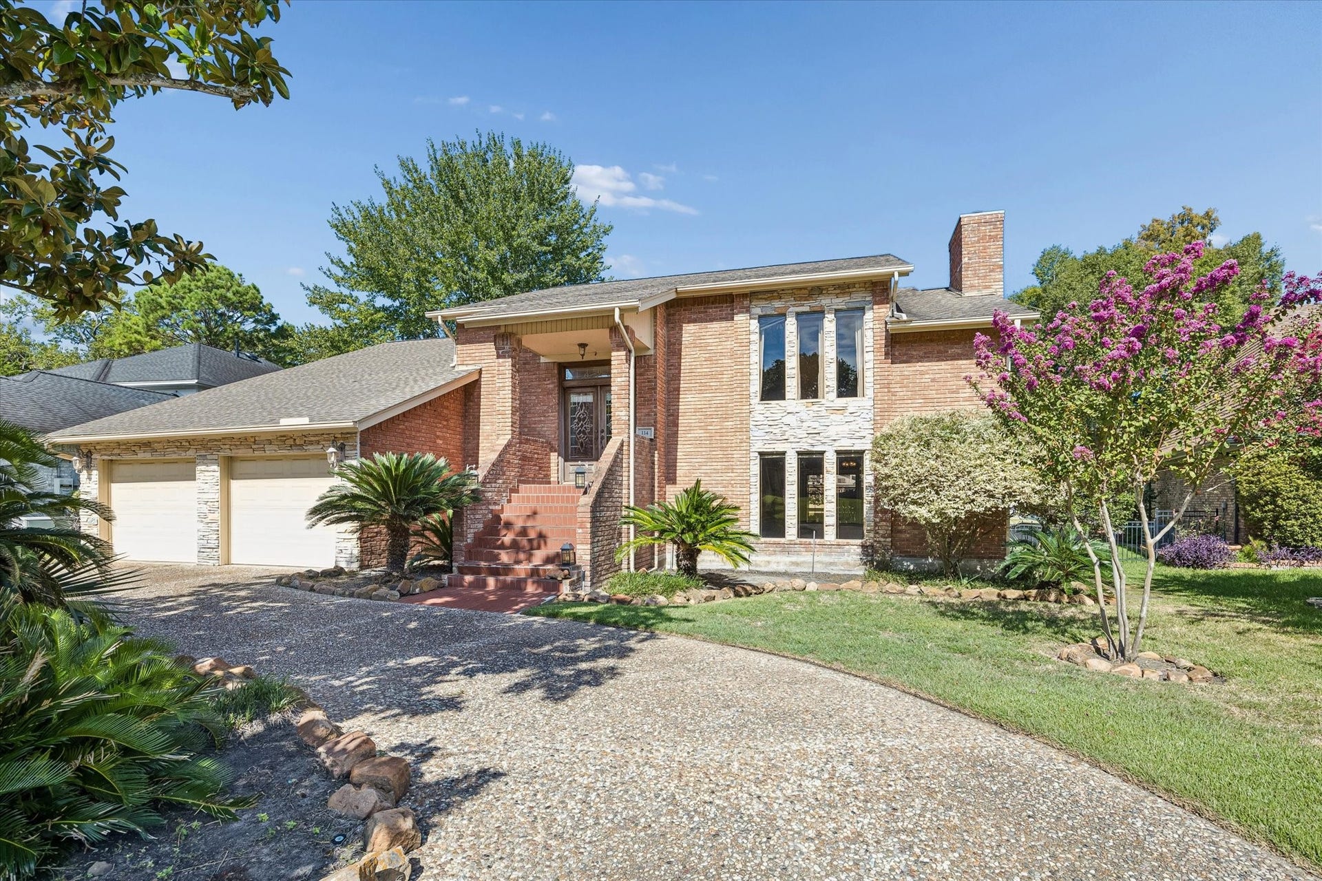 Welcoming front exterior with mature landscaping and a circular driveway providing convenient additional parking.