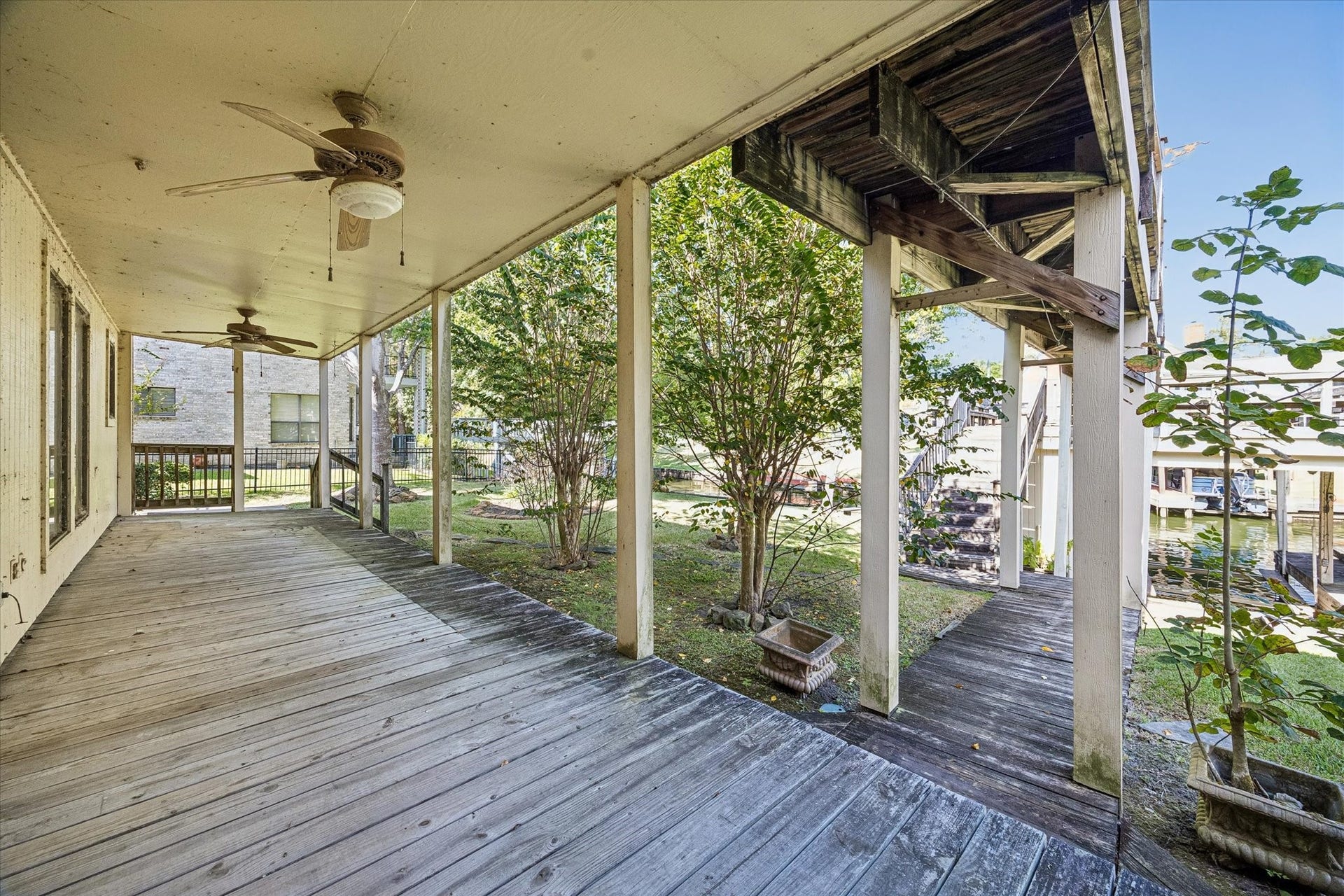 Covered downstairs deck extends the living space outdoors with views across the backyard toward the waterfront.