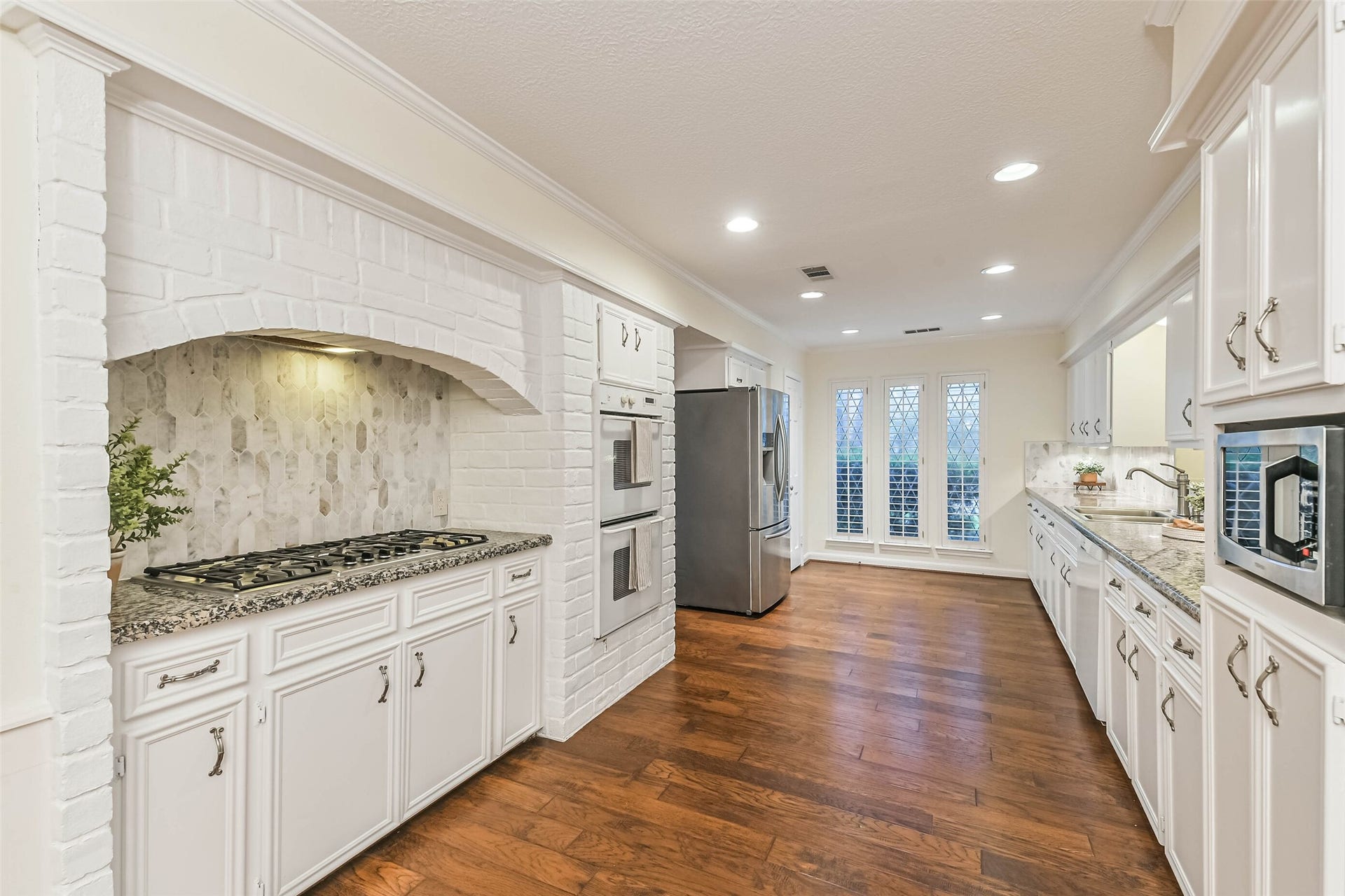 Long open kitchen with large stovetop, double ovens and long counter space.