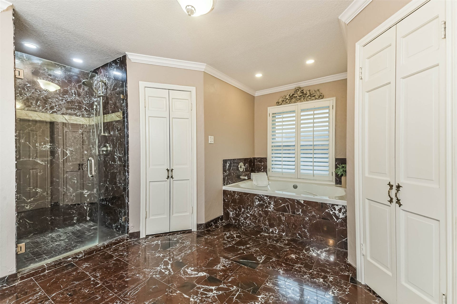 Spacious primary bathroom with separate shower and tub, double closets, custom marble.