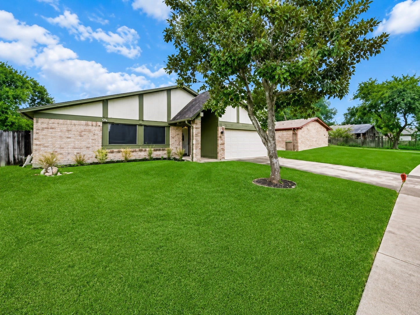 1707 Stone Lake Drive, Missouri City, TX 77489 Spacious front yard with mature landscaping, offering another view of the homes exterior and attached two-car garage.