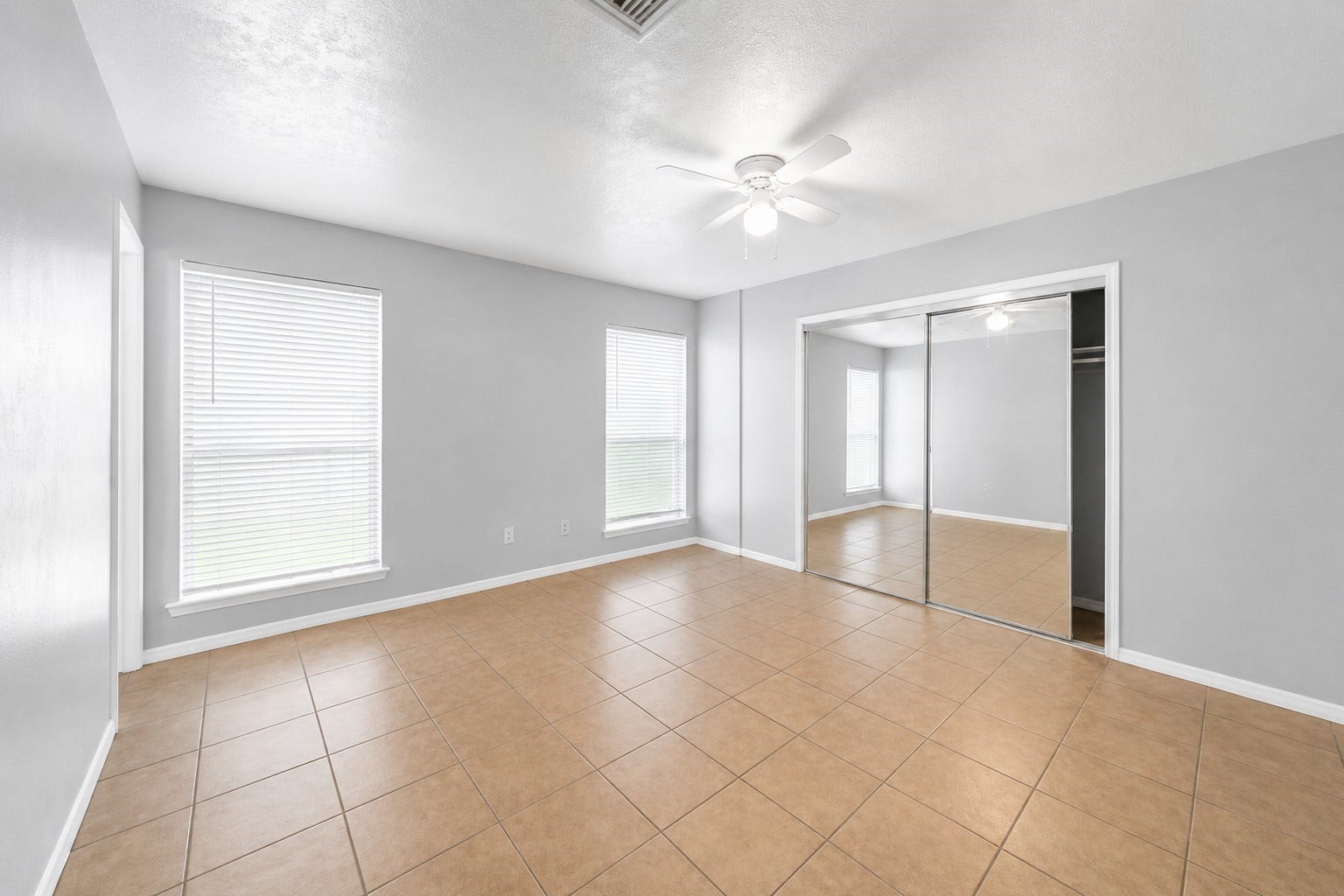 1707 Stone Lake Drive, Missouri City, TX 77489 Spacious primary bedroom featuring tile flooring, abundant natural light, and a large mirrored closet.