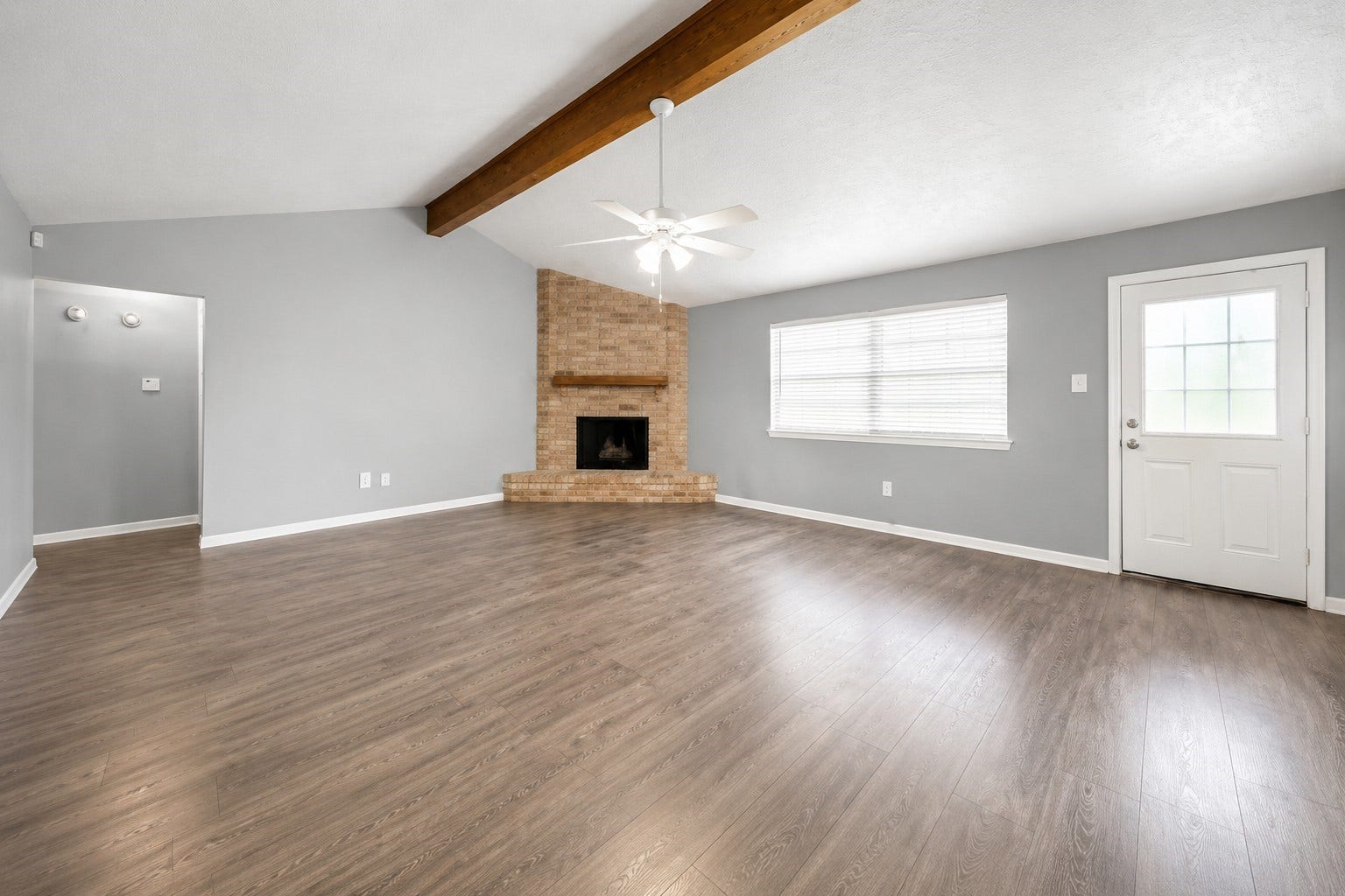 1707 Stone Lake Drive, Missouri City, TX 77489 Spacious living area featuring vaulted ceilings, exposed wood beam, brick fireplace, and plenty of natural light.