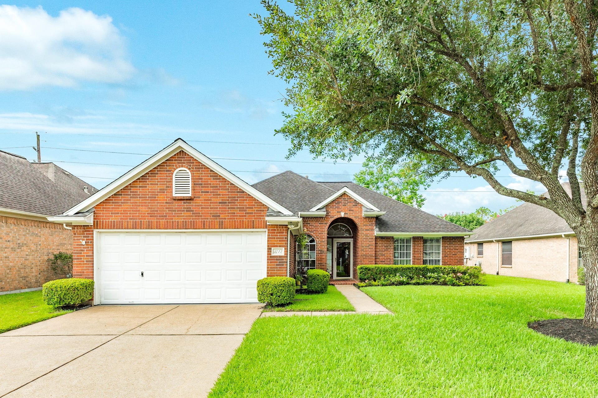3722 S Peach Hollow Circle, Pearland, TX 77584 Classic brick exterior, manicured landscaping, and a welcoming covered entry with an arched front porch. Mature shrubs and an attached two-car garage create an attractive first impression in this established 55+ golf course neighborhood.