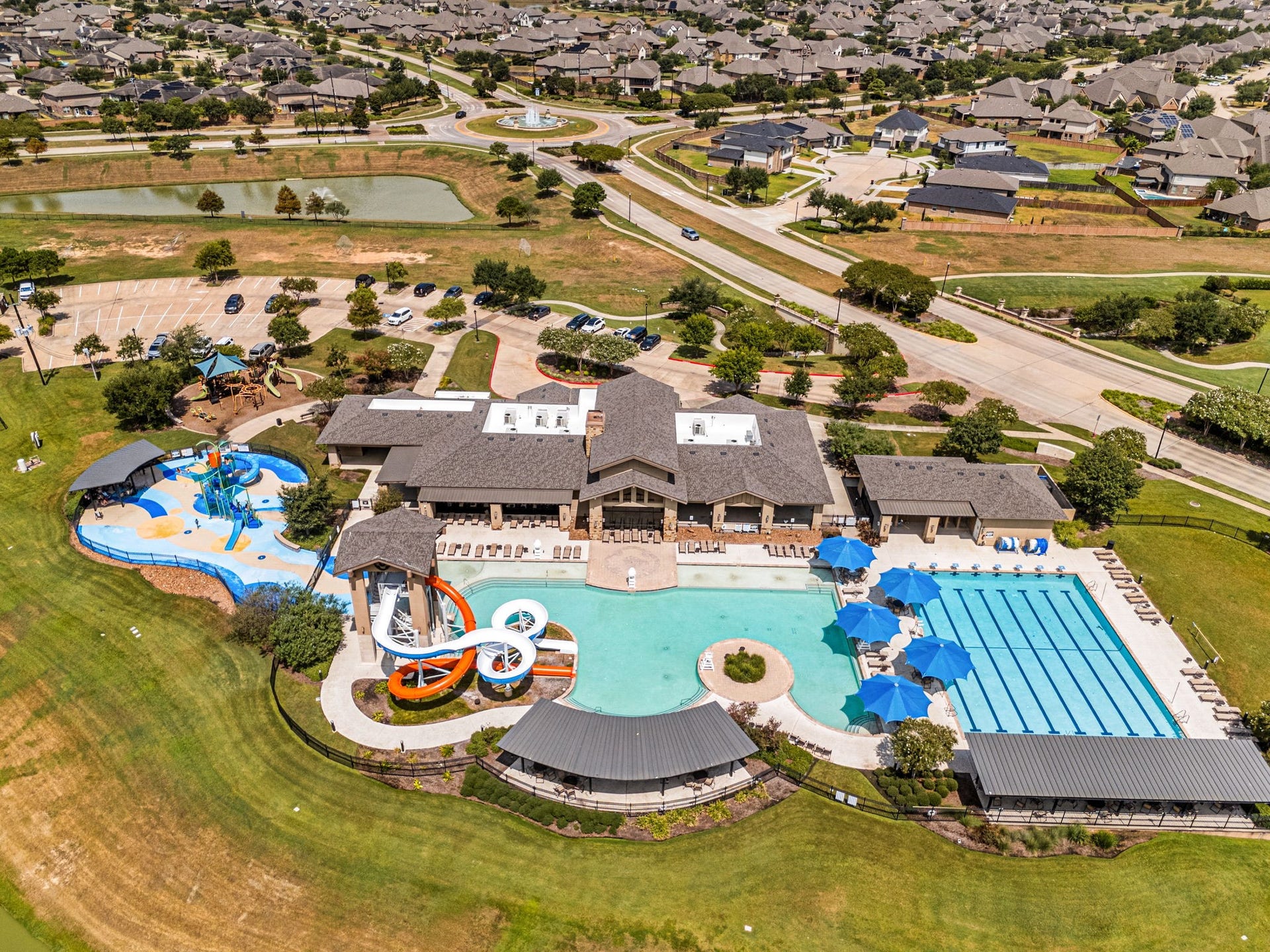 3815 Favor Forest Court, Katy, TX 77494 Tamarrons resort-style amenity complex features a resort pool with water slides and splash features, a dedicated lap pool, shaded seating areas, and an adjacent playground, offering plenty of ways to swim, play, and spend time outdoors.