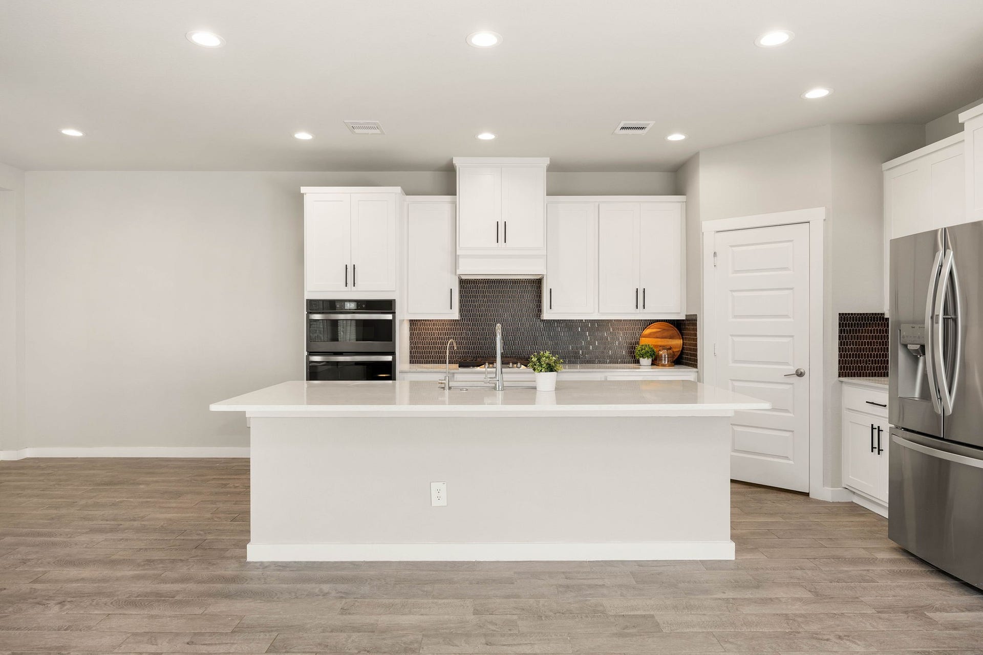 3815 Favor Forest Court, Katy, TX 77494 A generous island, gleaming quartz countertops, and a designer tile backsplash anchor the kitchen, complemented by stainless-steel appliances and a double oven.