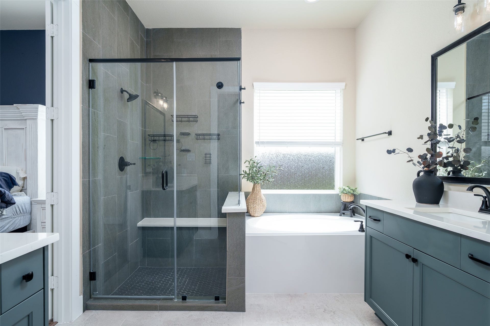 3348 Voda Bend Drive, Katy, TX 77493 The primary bathroom is a luxurious haven, featuring a tiled walk-in shower, a spacious bathtub for ultimate relaxation, and double sink vanities with sleek custom paint adorned with modern black hardware for a stylish touch.