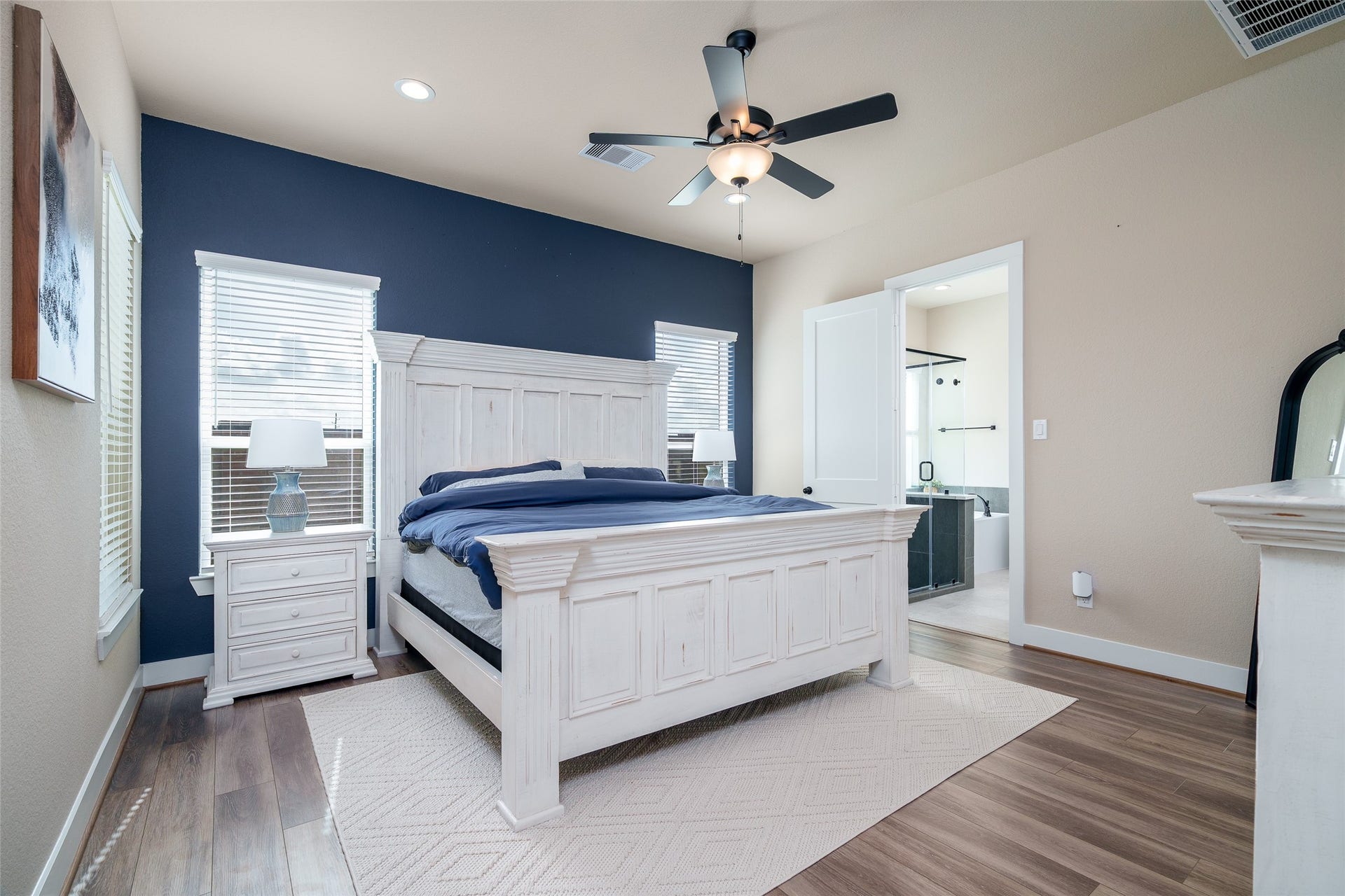 3348 Voda Bend Drive, Katy, TX 77493 Retreat to the serene primary bedroom, featuring windows with privacy blinds, elegant vinyl plank flooring, custom accent wall, and a stylish ceiling fan for ultimate comfort and relaxation!