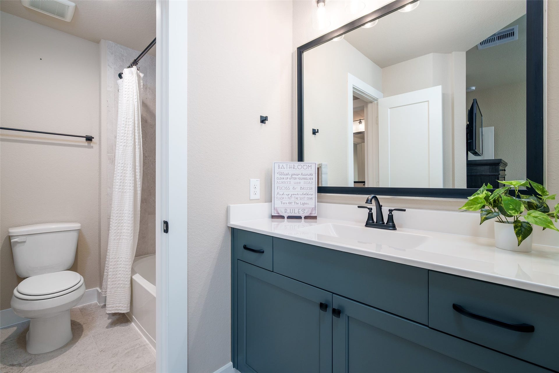 3348 Voda Bend Drive, Katy, TX 77493 This bedrooms private sink area showcases a custom-painted vanity with a framed mirror, that conveniently connects to a shared bathroom featuring a shower/tub combo and toilet, providing comfort and ease for daily living.