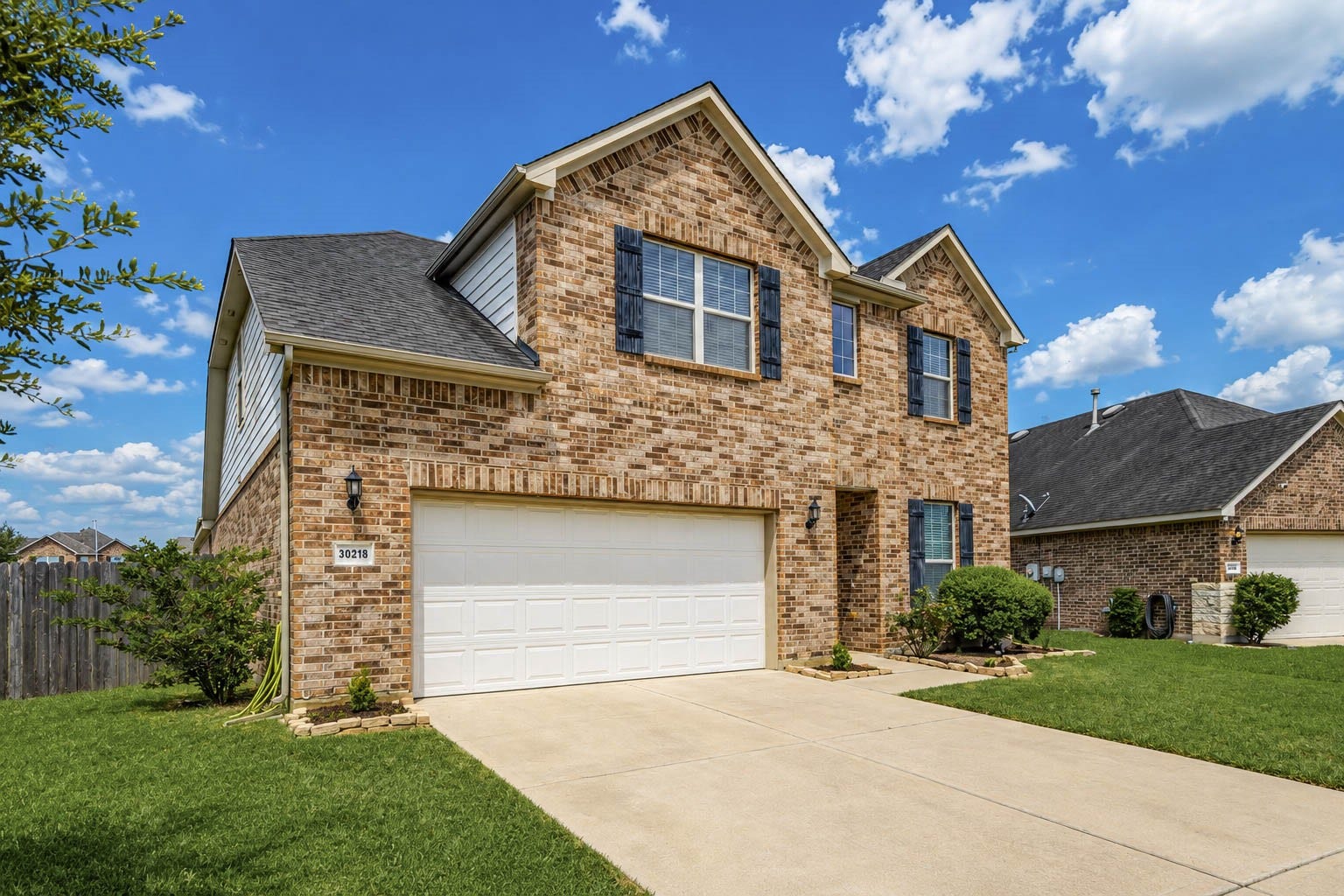 30218 Creekside Drive, Brookshire, TX 77423 Well maintained two-story brick home with a spacious two-car garage, accented by dark shutters and surrounded by a well-kept lawn.