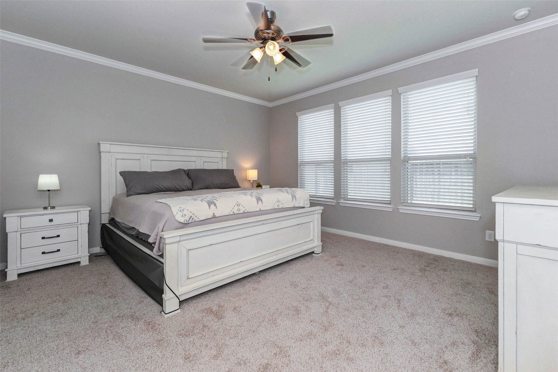 30218 Creekside Drive, Brookshire, TX 77423 Spacious primary bedroom with new carpet, featuring a ceiling fan and ample natural light from three large windows.
