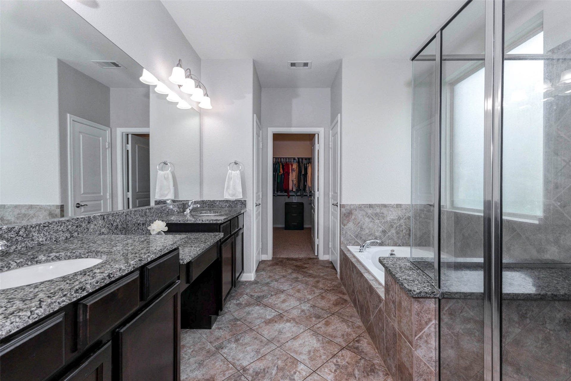 30218 Creekside Drive, Brookshire, TX 77423 Another view of the primary bathroom featuring dual granite sinks, elegant tile flooring, a spacious walk-in shower, and a relaxing bathtub with ample natural light.