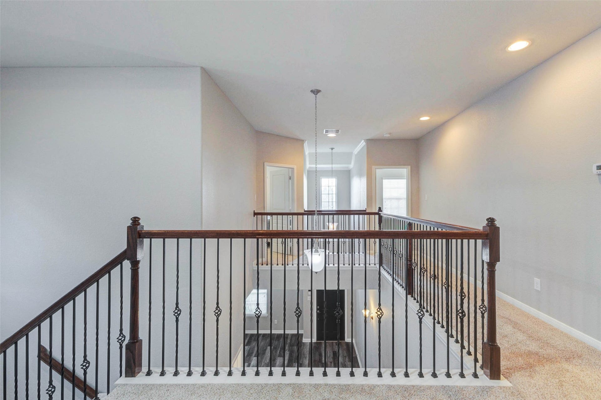 30218 Creekside Drive, Brookshire, TX 77423 Elegant upstairs landing with stylish wrought iron railing, plush carpeting, and modern recessed lighting, offering a bright and open ambiance.