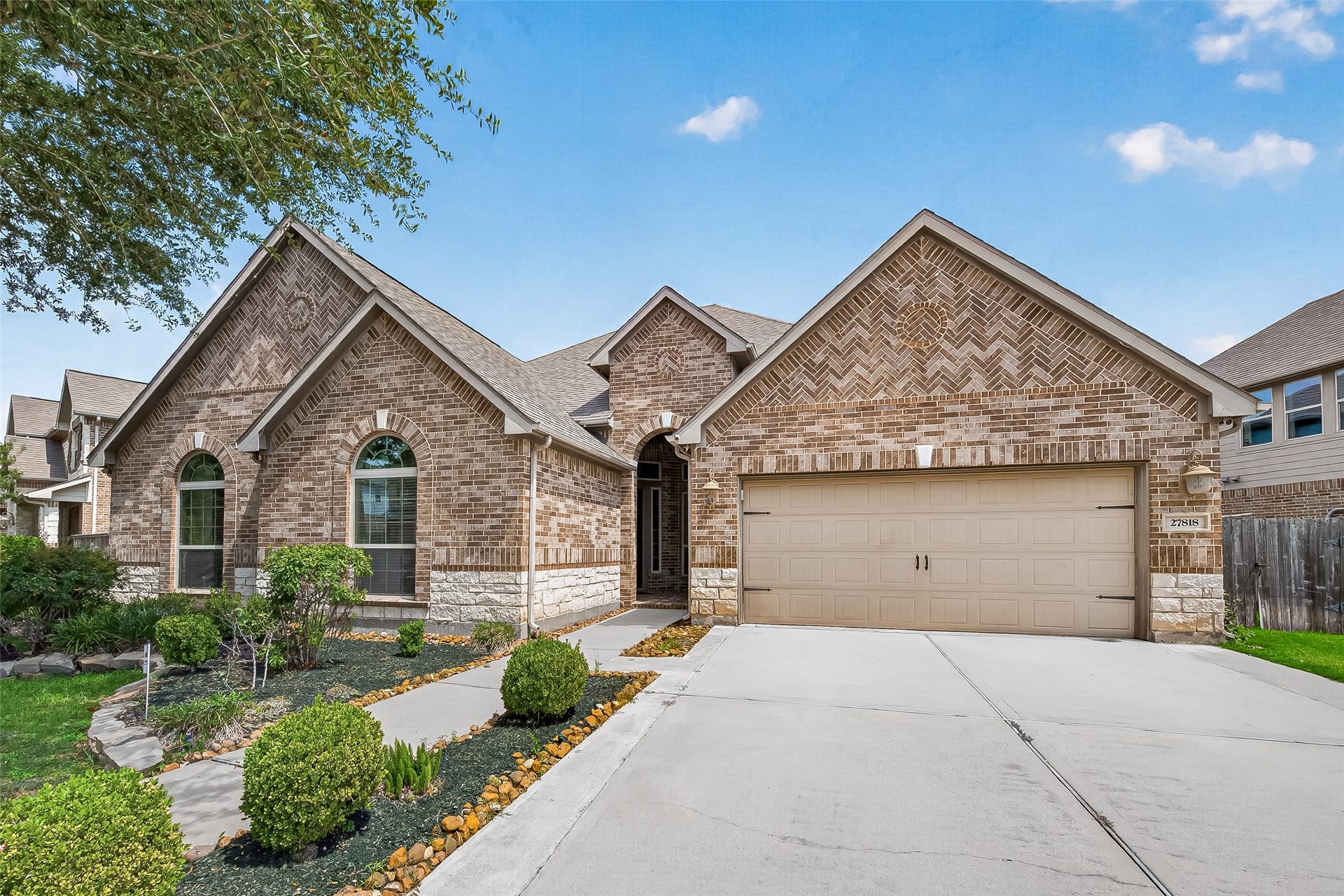 27818 Tamara Branch Lane, Katy, TX 77494 Nestled in the highly sought-after Cinco Ranch community, this stunning 1.5-story home showcases exceptional curb appeal with a beautiful stone elevation, lush landscaping, and architectural details that create a lasting first impression. A welcoming front porch with elegant dual wood front doors featuring wrought iron detailing sets the tone for the sophistication found throughout.