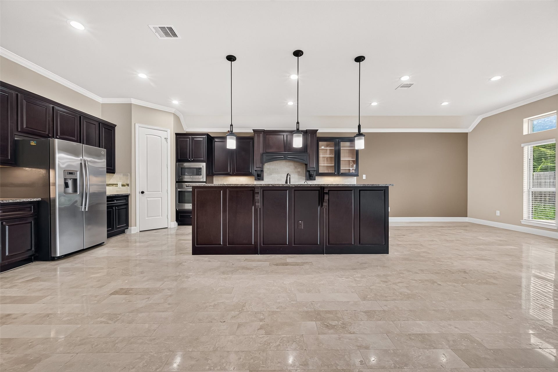 27818 Tamara Branch Lane, Katy, TX 77494 Kitchen: The open-concept island kitchen is designed for both everyday living and entertaining, featuring granite countertops, pendant lighting, rich dark wood cabinetry with upgraded display cabinets, extensive countertop space, built-in stainless steel appliances, a gas cooktop, and a beautiful tile backsplash with decorative accent tiles.