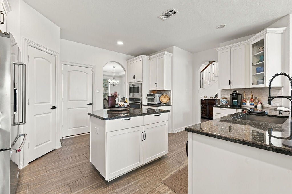9918 Hubble Drive, Iowa Colony, TX 77583 Modern kitchen with sleek white cabinetry, granite countertops, and a central island. Stainless steel appliances and an open layout enhance functionality and style.