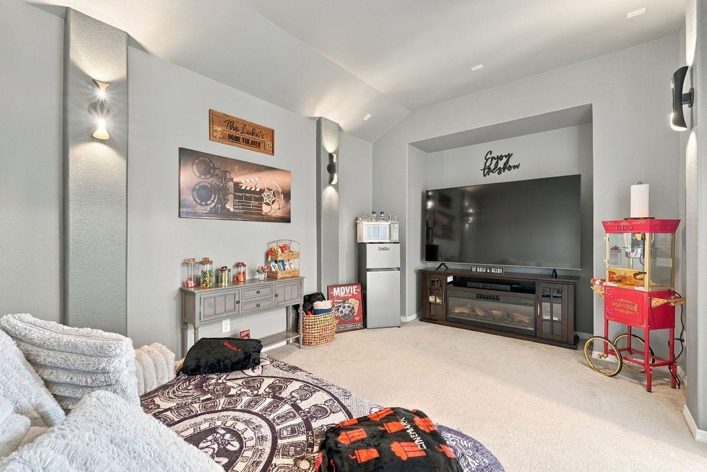 9918 Hubble Drive, Iowa Colony, TX 77583 Cozy home theater featuring surround sound, a large screen, ambient lighting, and a popcorn machine, perfect for movie nights.