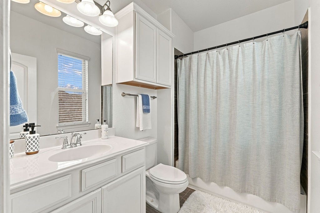 9918 Hubble Drive, Iowa Colony, TX 77583 Bright and inviting bathroom featuring sleek white cabinetry, a modern vanity with ample counter space, and a full shower-tub combo with a stylish curtain.