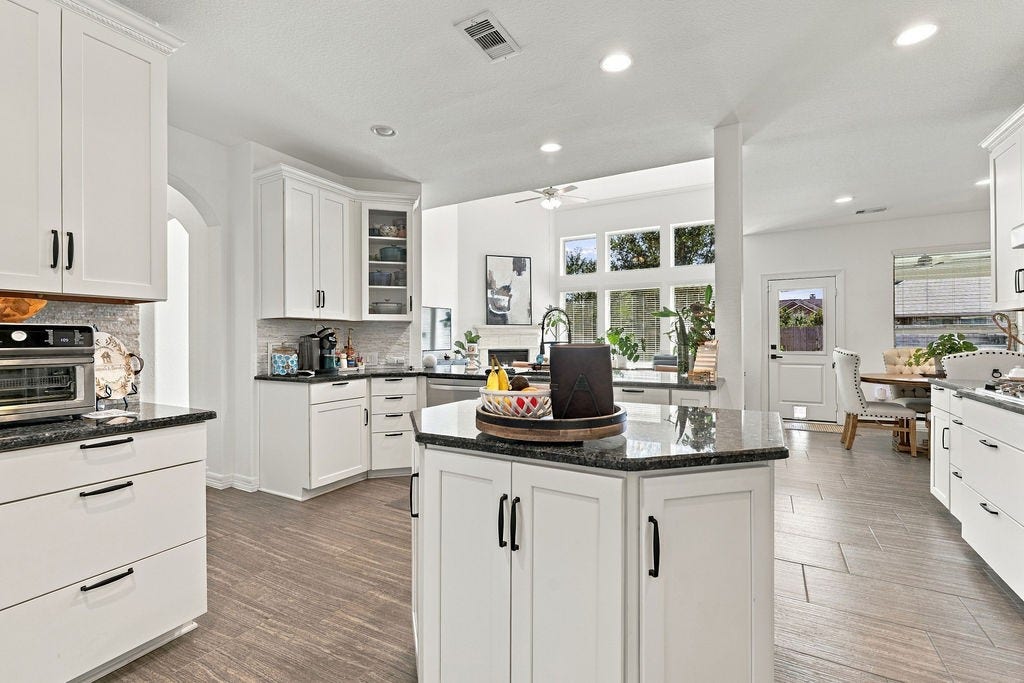 9918 Hubble Drive, Iowa Colony, TX 77583 Spacious kitchen featuring sleek white cabinetry, granite countertops, and abundant natural light, seamlessly flowing into a cozy dining area.