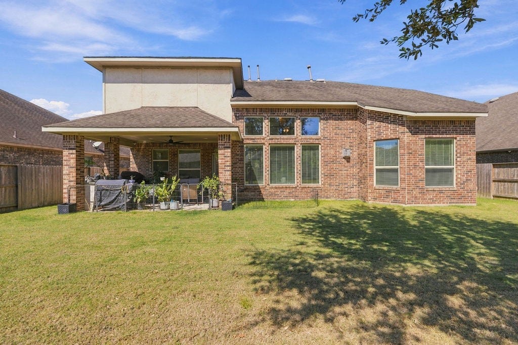9918 Hubble Drive, Iowa Colony, TX 77583 Spacious backyard with a covered patio and brick exterior, perfect for outdoor entertaining and relaxation.