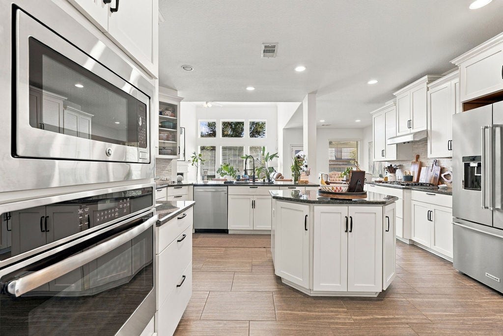 9918 Hubble Drive, Iowa Colony, TX 77583 Spacious kitchen with sleek stainless steel appliances, elegant white cabinetry, and a central island perfect for meal prep and entertaining.