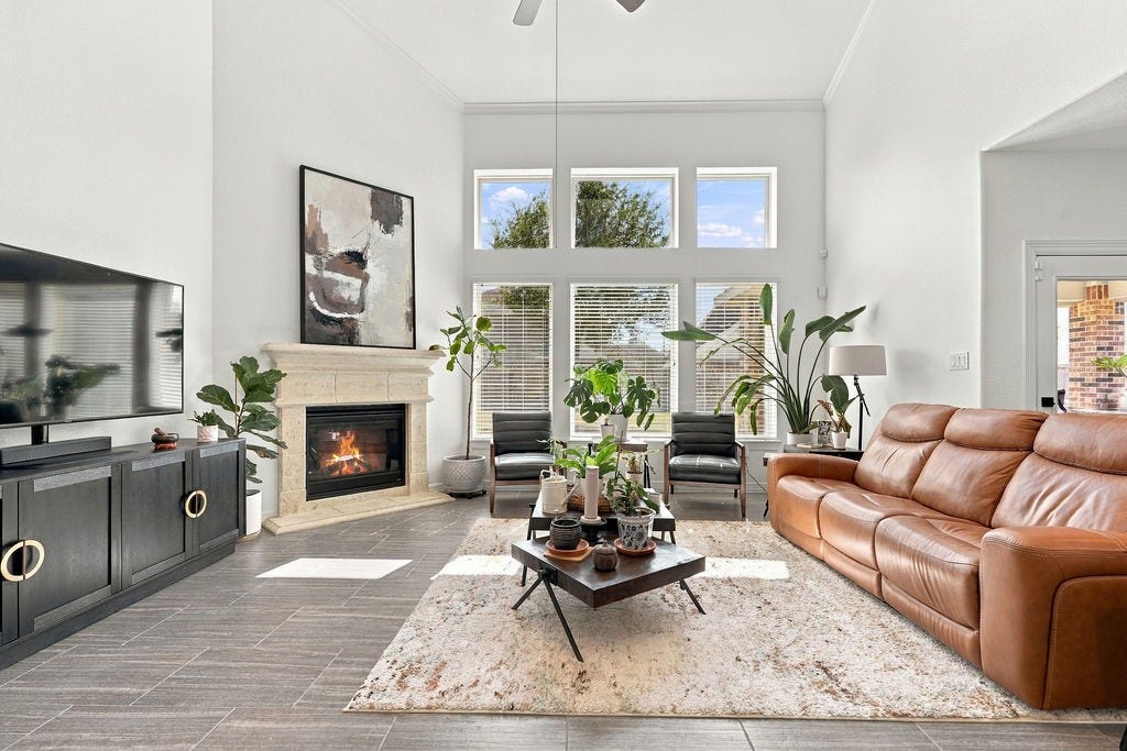 9918 Hubble Drive, Iowa Colony, TX 77583 Spacious living room with high ceilings, large windows, and abundant natural light. A cozy fireplace anchors the room, complemented by modern furnishings and elegant decor.