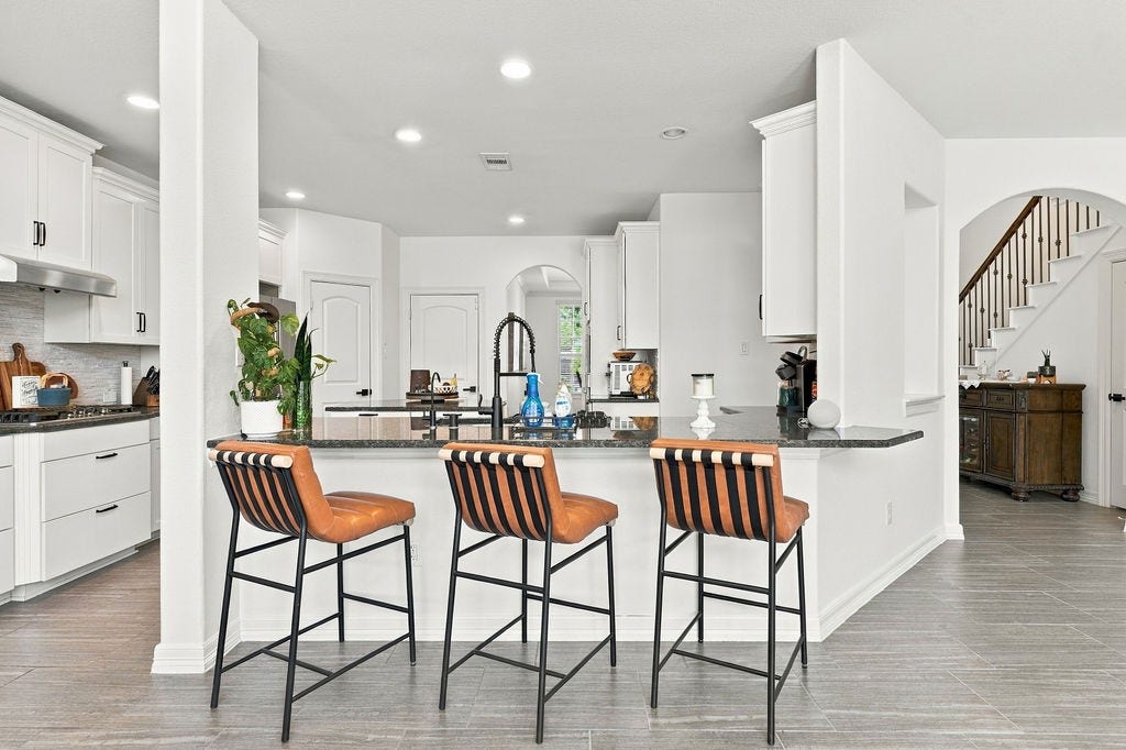9918 Hubble Drive, Iowa Colony, TX 77583 Modern kitchen featuring sleek white cabinetry, a large island with stylish bar seating, and elegant granite countertops, perfect for entertaining and culinary adventures.