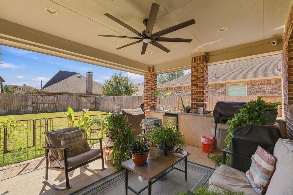 9918 Hubble Drive, Iowa Colony, TX 77583 Charming covered patio perfect for relaxing and entertaining, featuring ceiling fan, outdoor seating, and built-in kitchen, all overlooking a spacious fenced backyard.