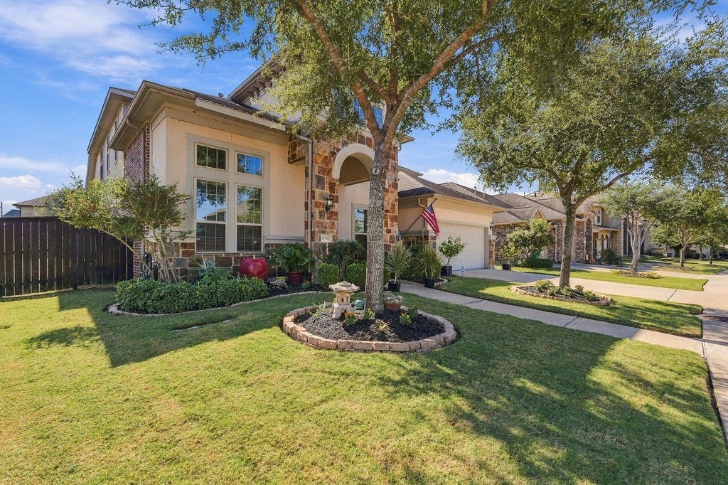 9918 Hubble Drive, Iowa Colony, TX 77583 Charming home with a stone-accented facade, well-manicured lawn, and inviting front garden, nestled in a peaceful neighborhood.