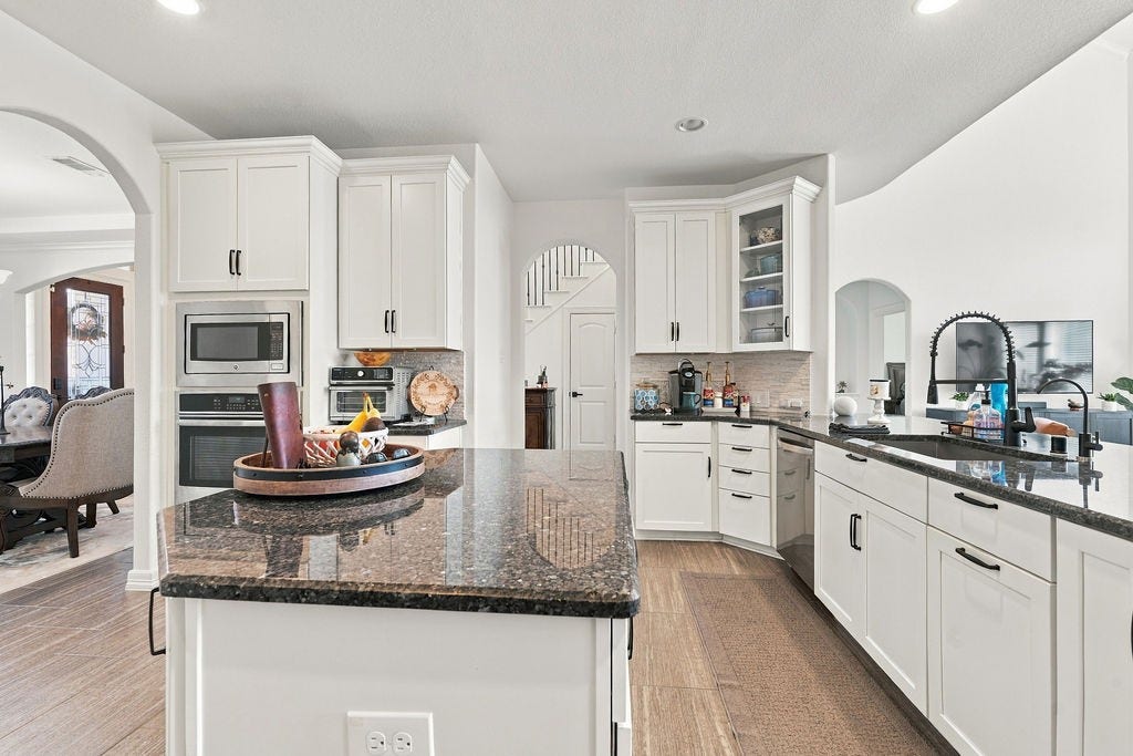 9918 Hubble Drive, Iowa Colony, TX 77583 Spacious kitchen with sleek granite countertops, modern appliances, and ample white cabinetry, offering both functionality and style.
