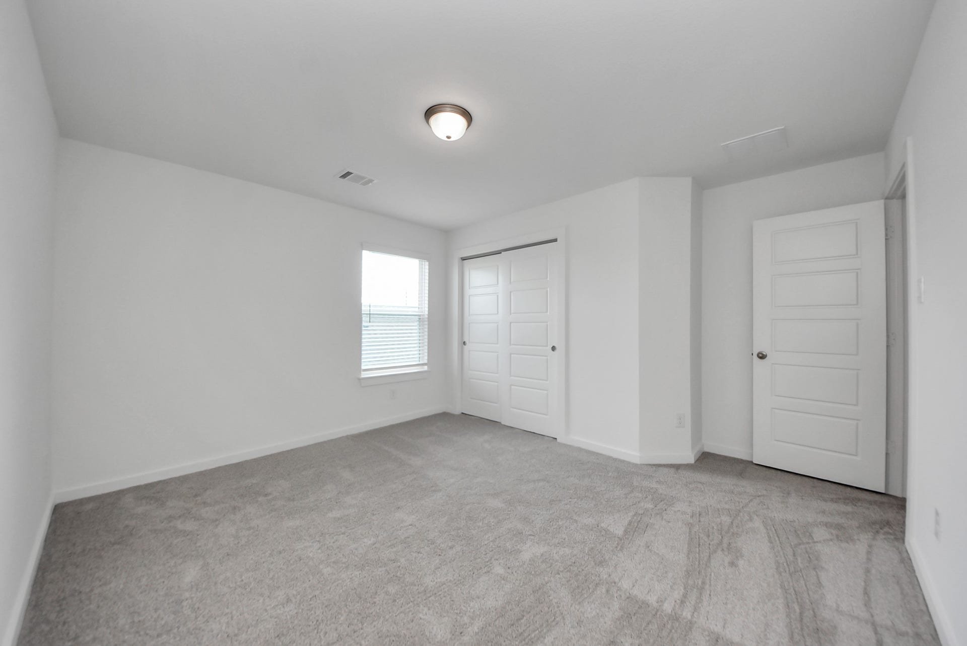 Secondary bedroom features plush carpeting, large windows that let in plenty of natural light, bright paint, and spacious closets.
