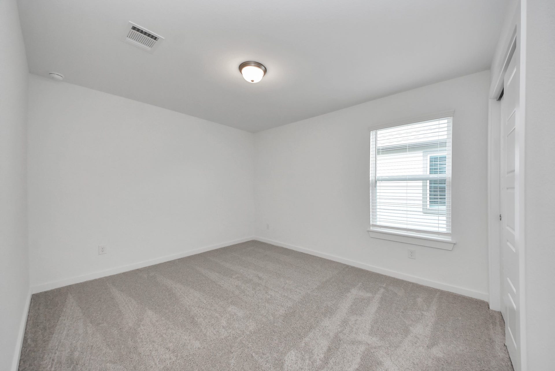 Secondary bedroom features plush carpeting, large windows that let in plenty of natural light, bright paint, and spacious closets.