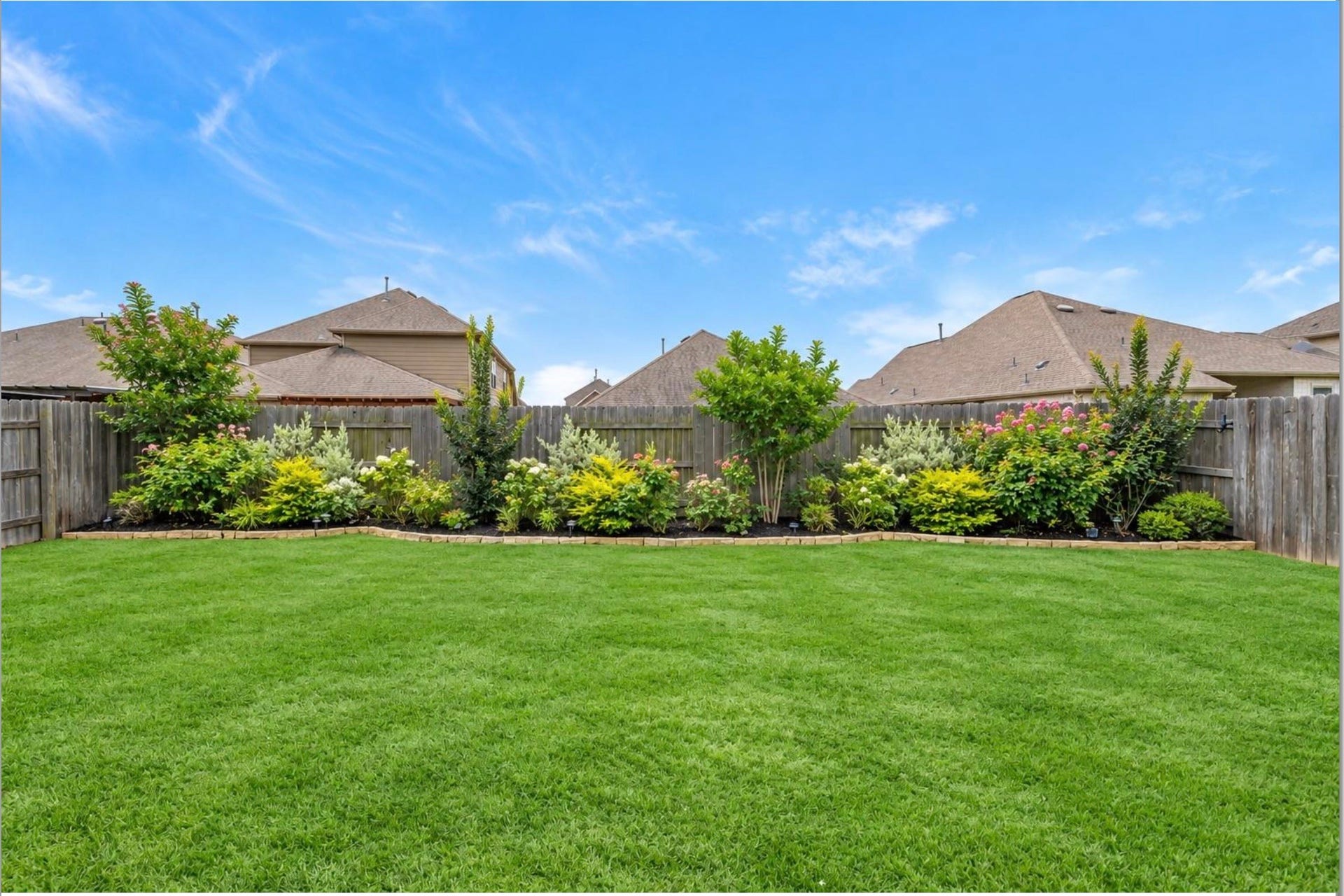 Generously sized fenced backyard with a lush green lawn and plenty of room for outdoor recreation, gardening, or future enhancements.