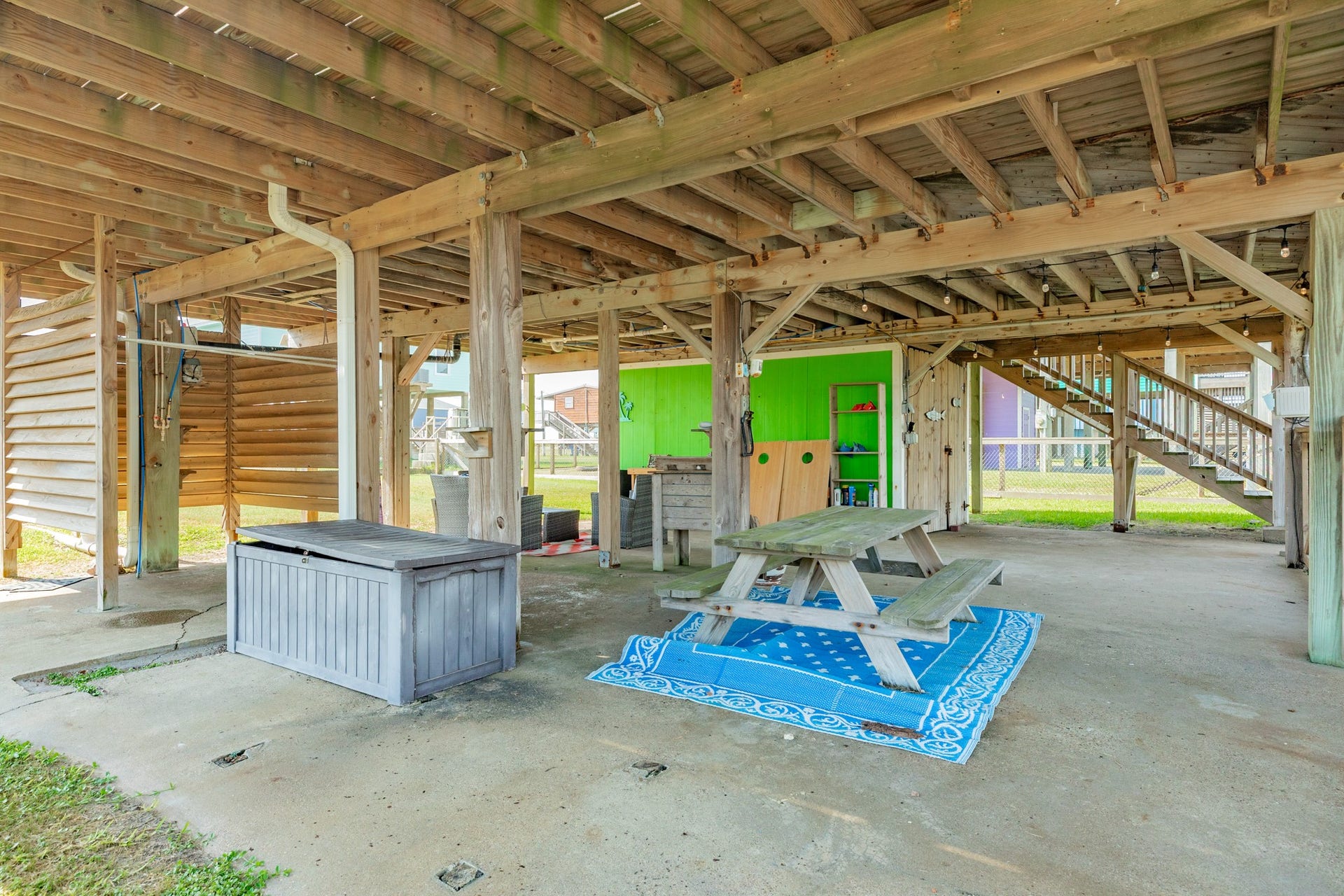 Another view highlights the generous shaded footprint beneath the elevated home, with space for a picnic table, seating, and outdoor storage.