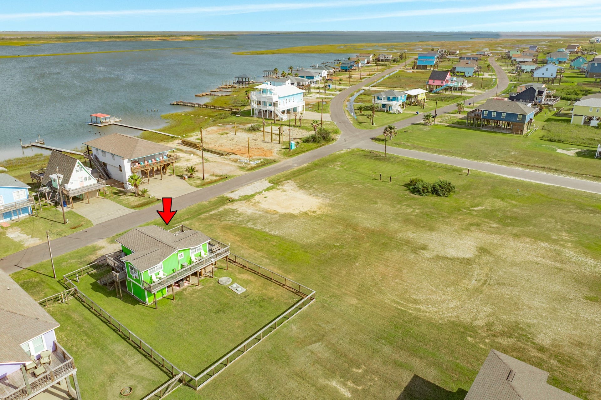 Wide aerial perspective highlights the propertys location near the water, surrounding open space, and neighborhood roadways.