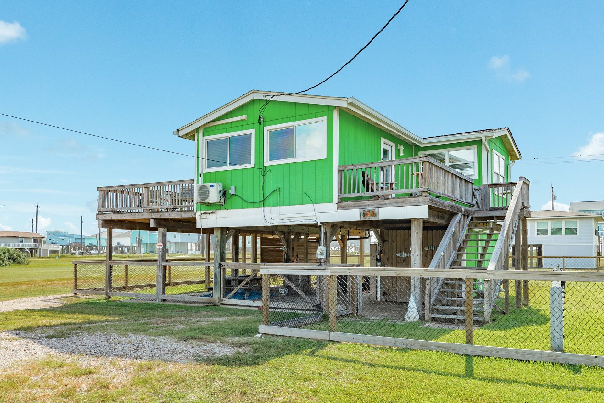 Another exterior angle highlights the homes bright green siding, elevated design, multiple deck areas, and exterior staircase.