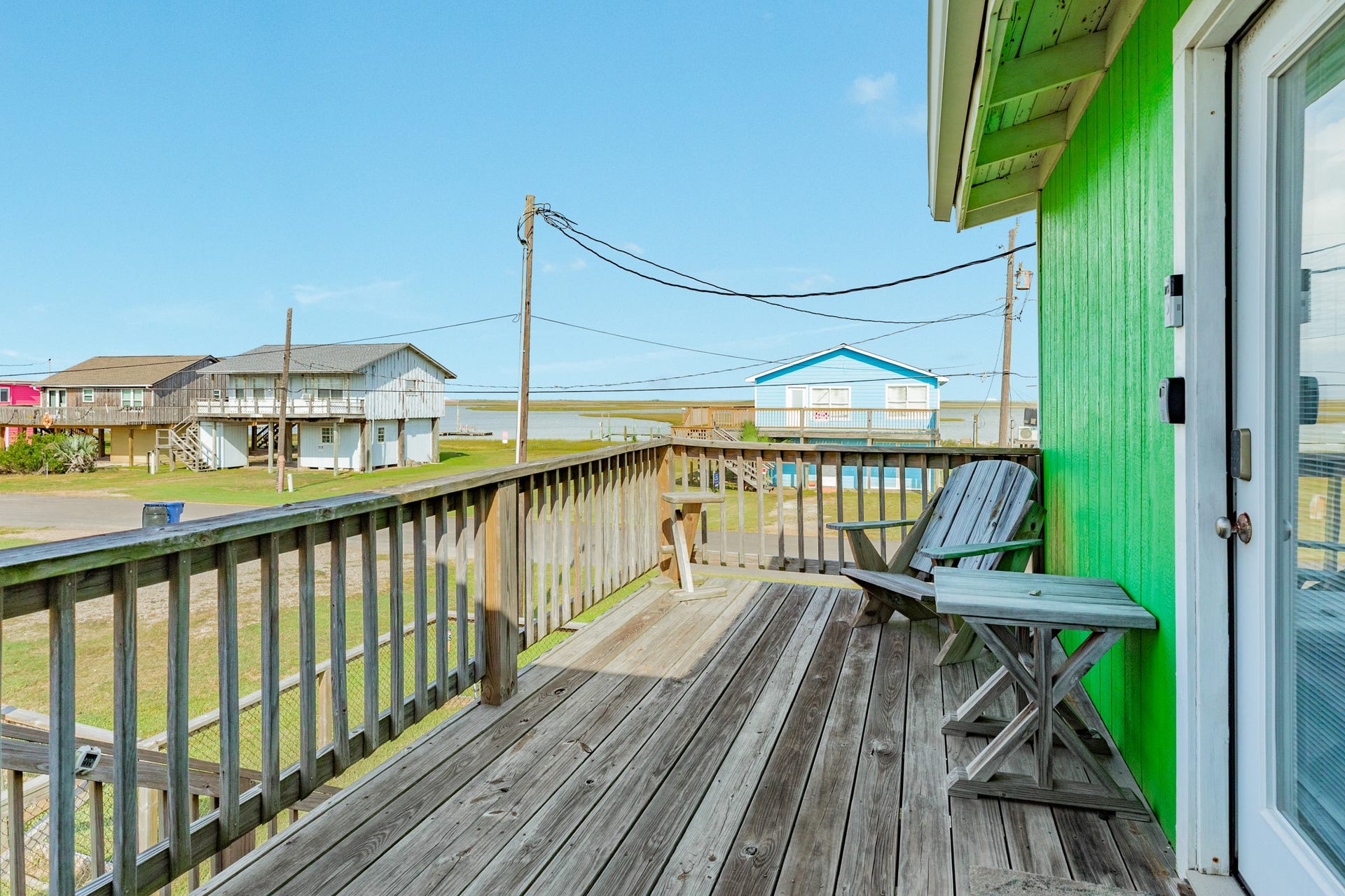 Wood deck provides additional outdoor seating with an open view toward the nearby water and surrounding coastal neighborhood.