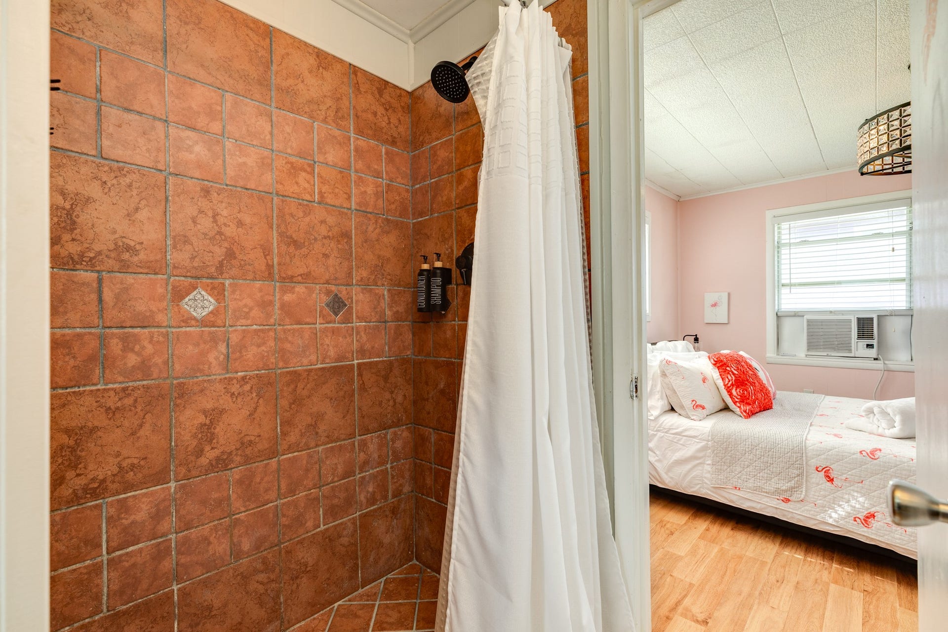 Tiled shower features warm earth-tone tilework, decorative accent tiles, and a rainfall-style showerhead.