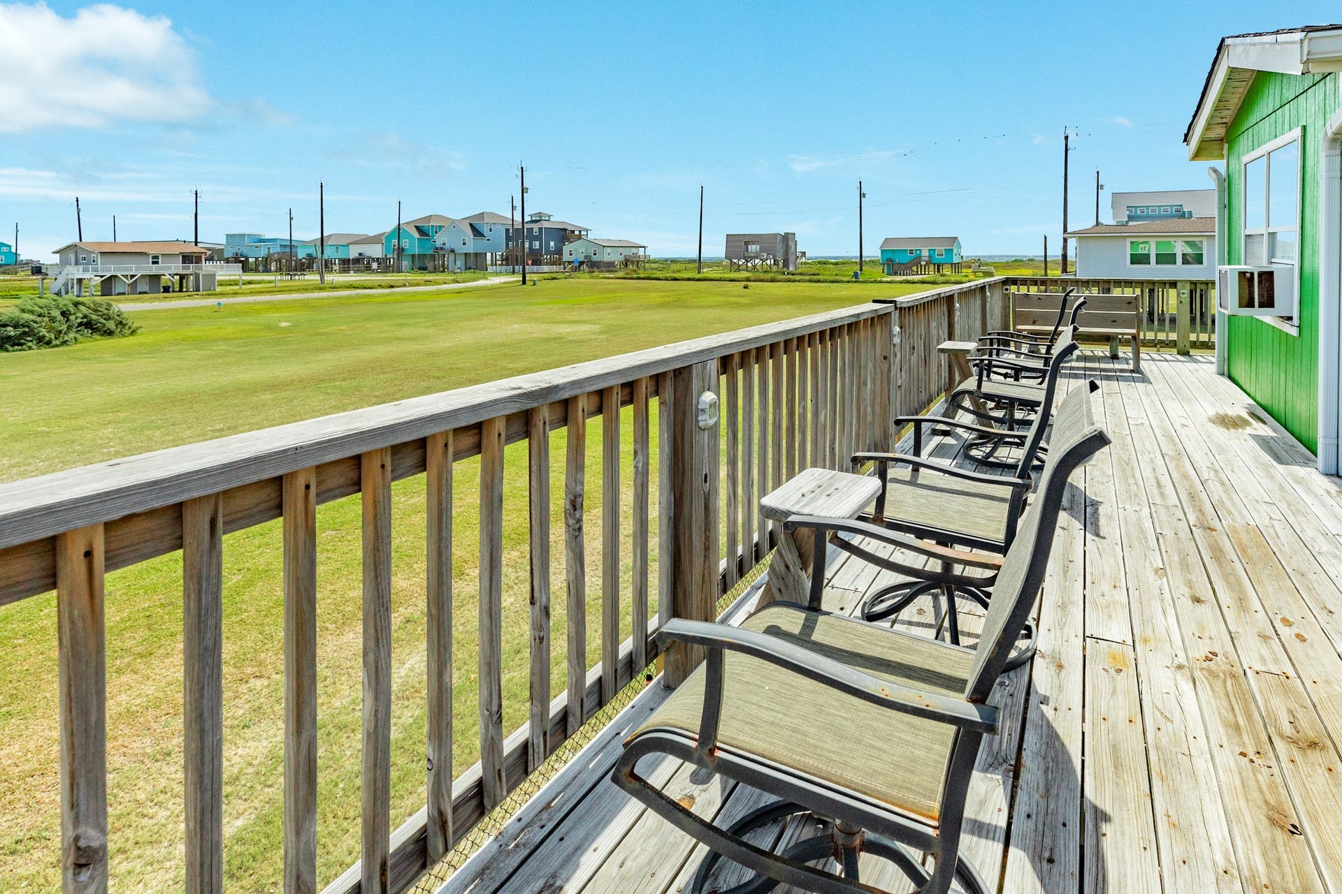 Long deck area overlooks a broad stretch of open green space, providing ample room for outdoor seating and relaxation.