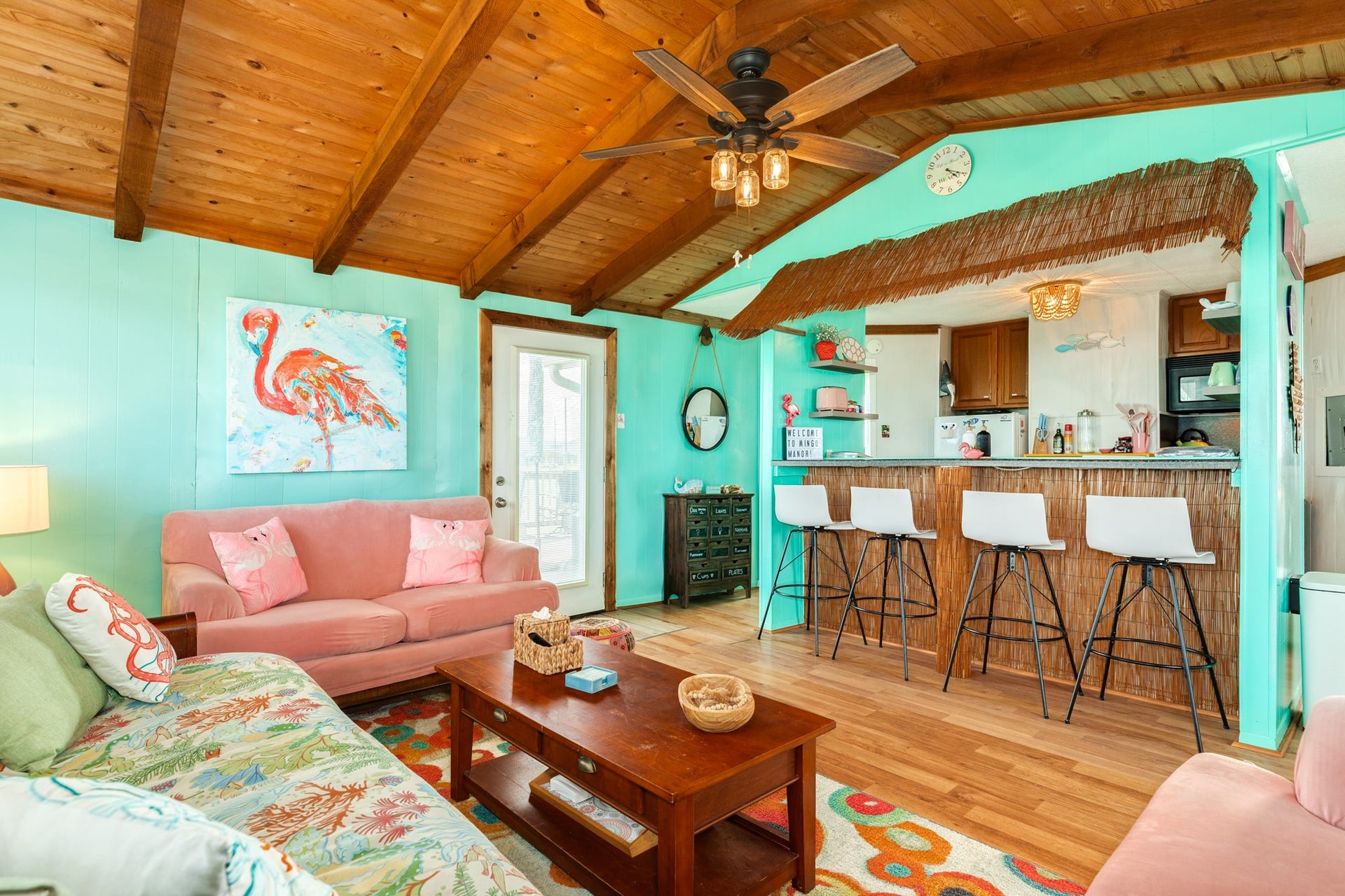 Open living space flows directly into the kitchen and breakfast bar, complemented by vaulted wood ceilings and a wall-mounted mini-split system.