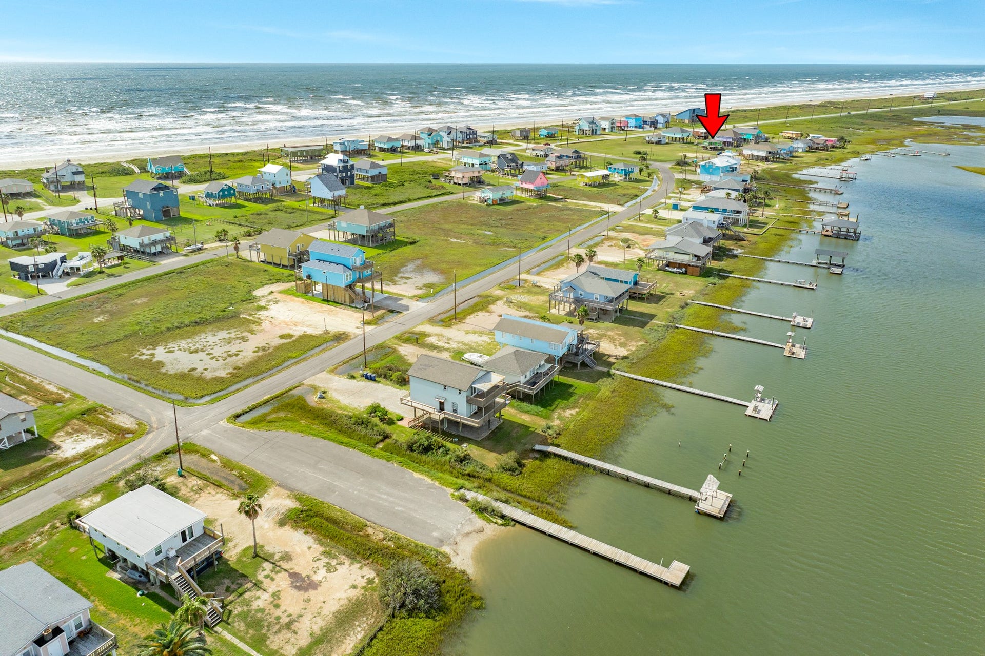 Panoramic aerial captures the surrounding neighborhood with the Gulf on one side and bay waters with numerous docks on the other.