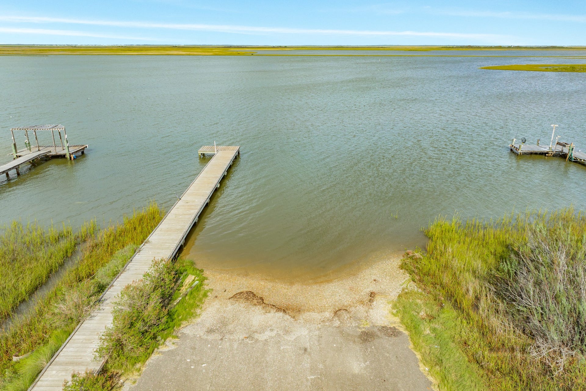Expansive water view showcases the nearby boat launch to Drum Bay shoreline, marsh grasses, and neighboring private docks.