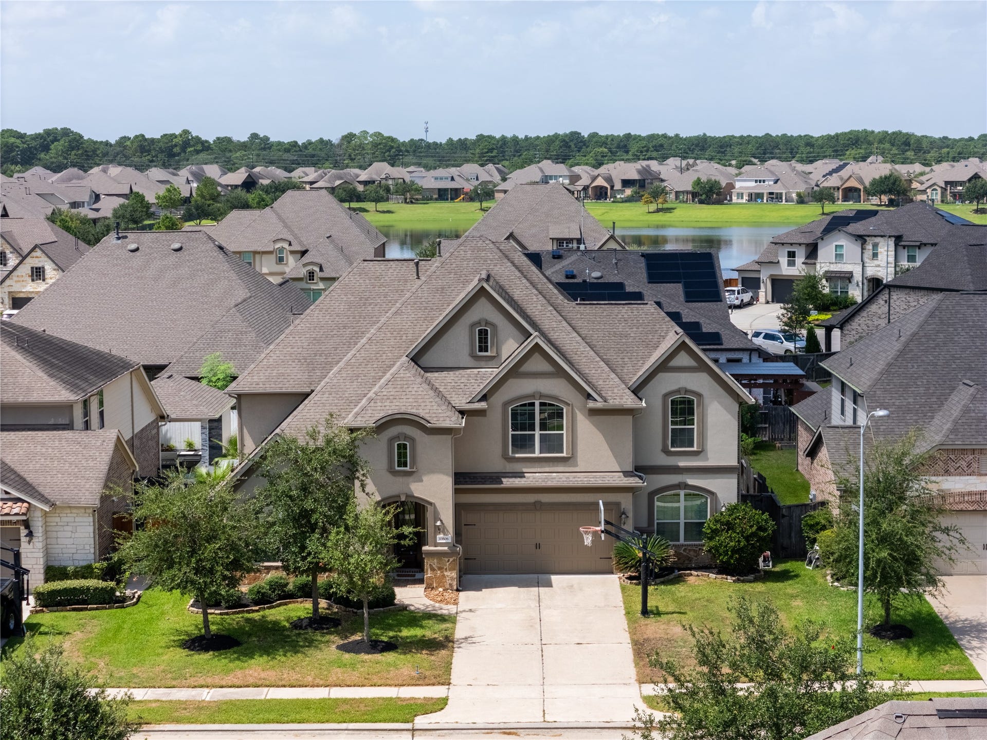 13506 COLUMBIA KEY Drive, Tomball, TX 77377 Striking curb appeal, a landscaped front yard, and a glimpse of the neighborhood lake beyond the rooftops.