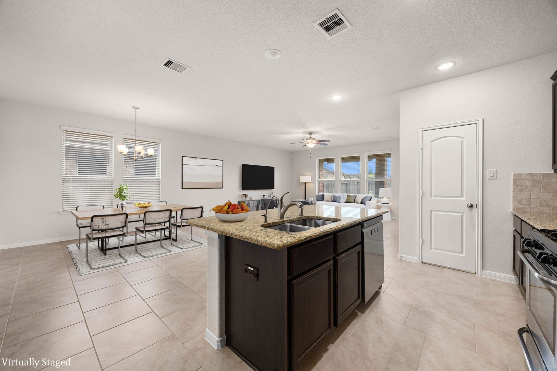 23643 Balzano Court, Katy, TX 77493 Bright and airy open-concept kitchen and dining area featuring a central granite-topped island with an integrated double sink and matching rich espresso cabinetry.