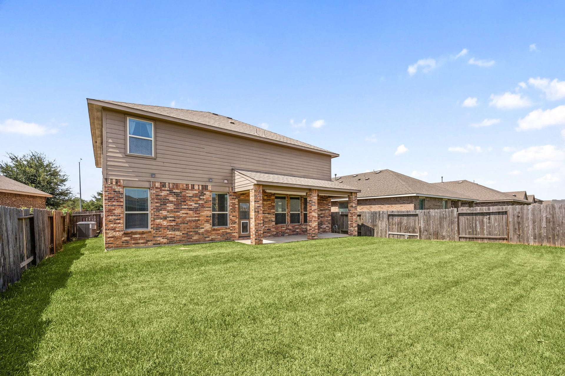 23643 Balzano Court, Katy, TX 77493 Impressive two-story rear exterior featuring a partial brick facade, a spacious covered porch, and a vast, fully fenced backyard.
