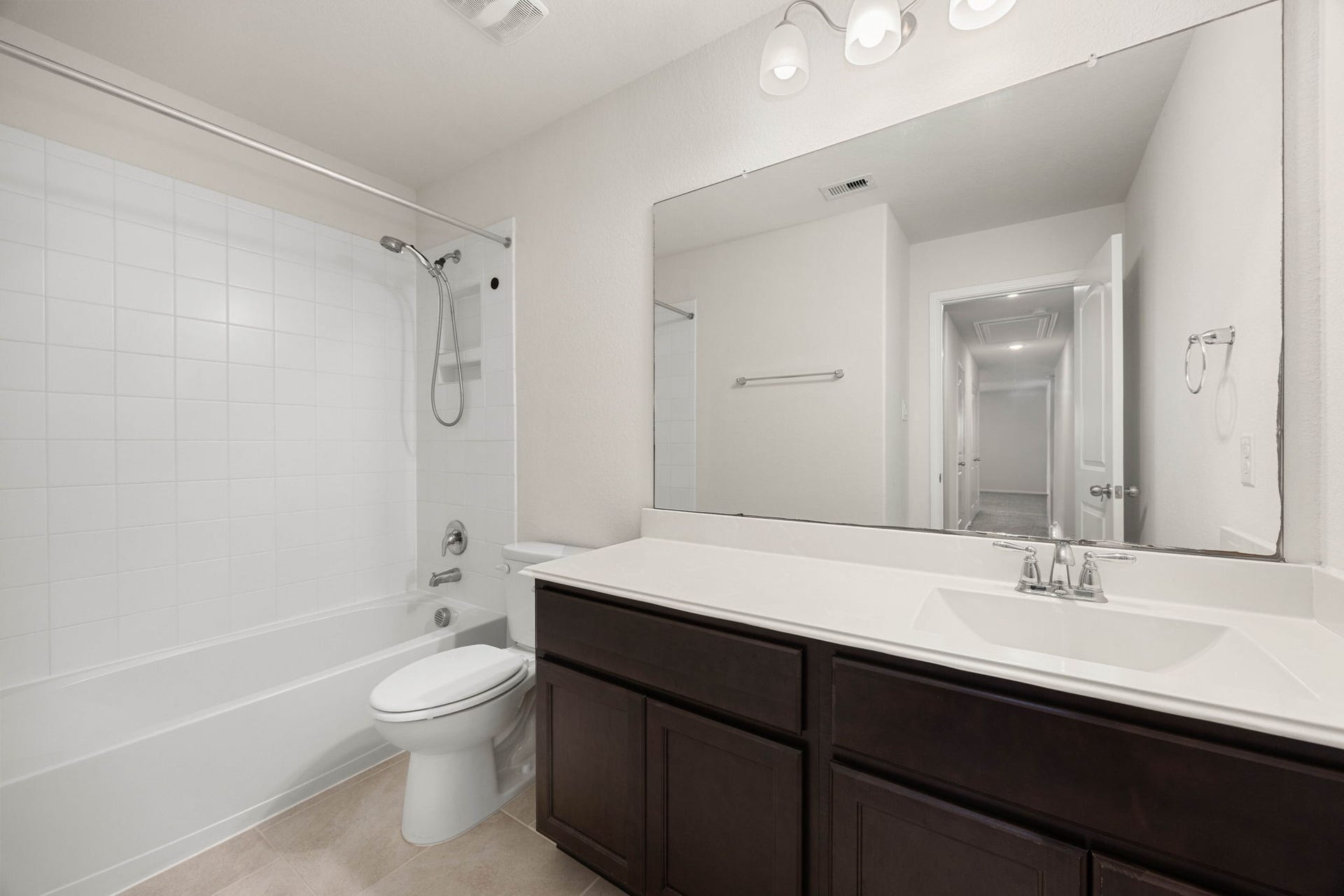 23643 Balzano Court, Katy, TX 77493 Pristine secondary full bathroom highlighting an expansive single-sink vanity, rich modern cabinetry, and a clean tub-to-ceiling tile surround.