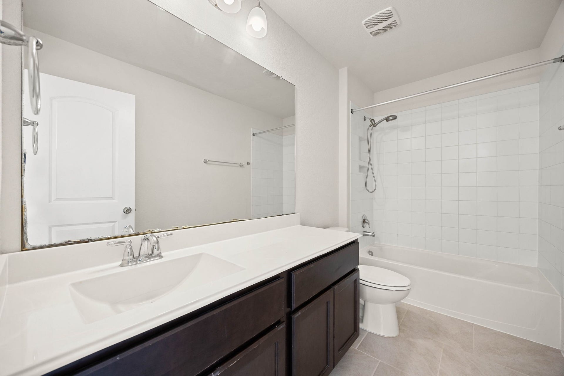 23643 Balzano Court, Katy, TX 77493 Crisp and modern secondary bathroom featuring a spacious vanity with integrated storage, an oversized mirror, and a classic tub-to-ceiling tile shower surround.
