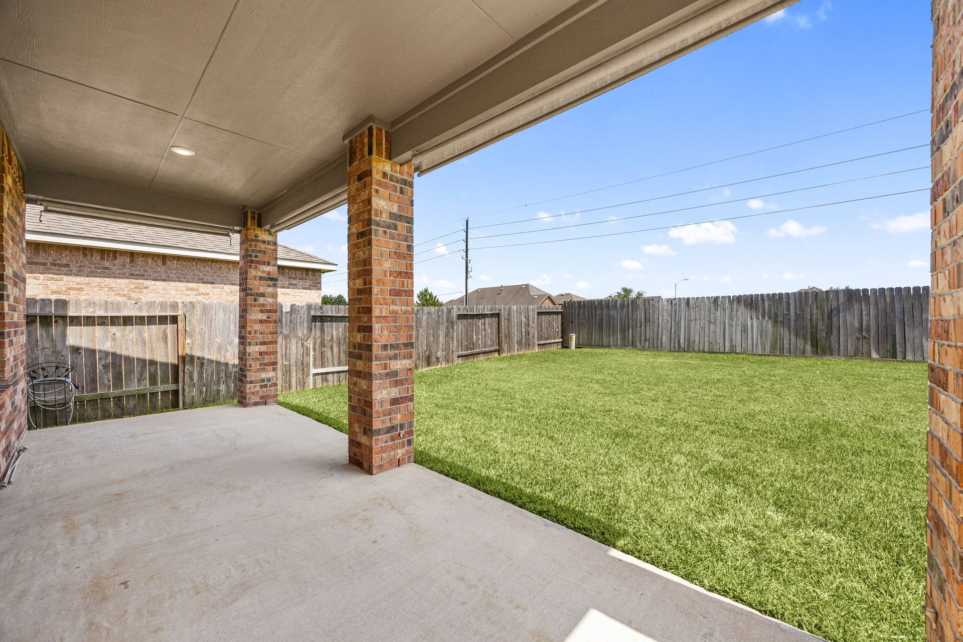 23643 Balzano Court, Katy, TX 77493 Expansive backyard retreat featuring a massive covered concrete patio, classic brick support pillars, and a fully fenced green lawn